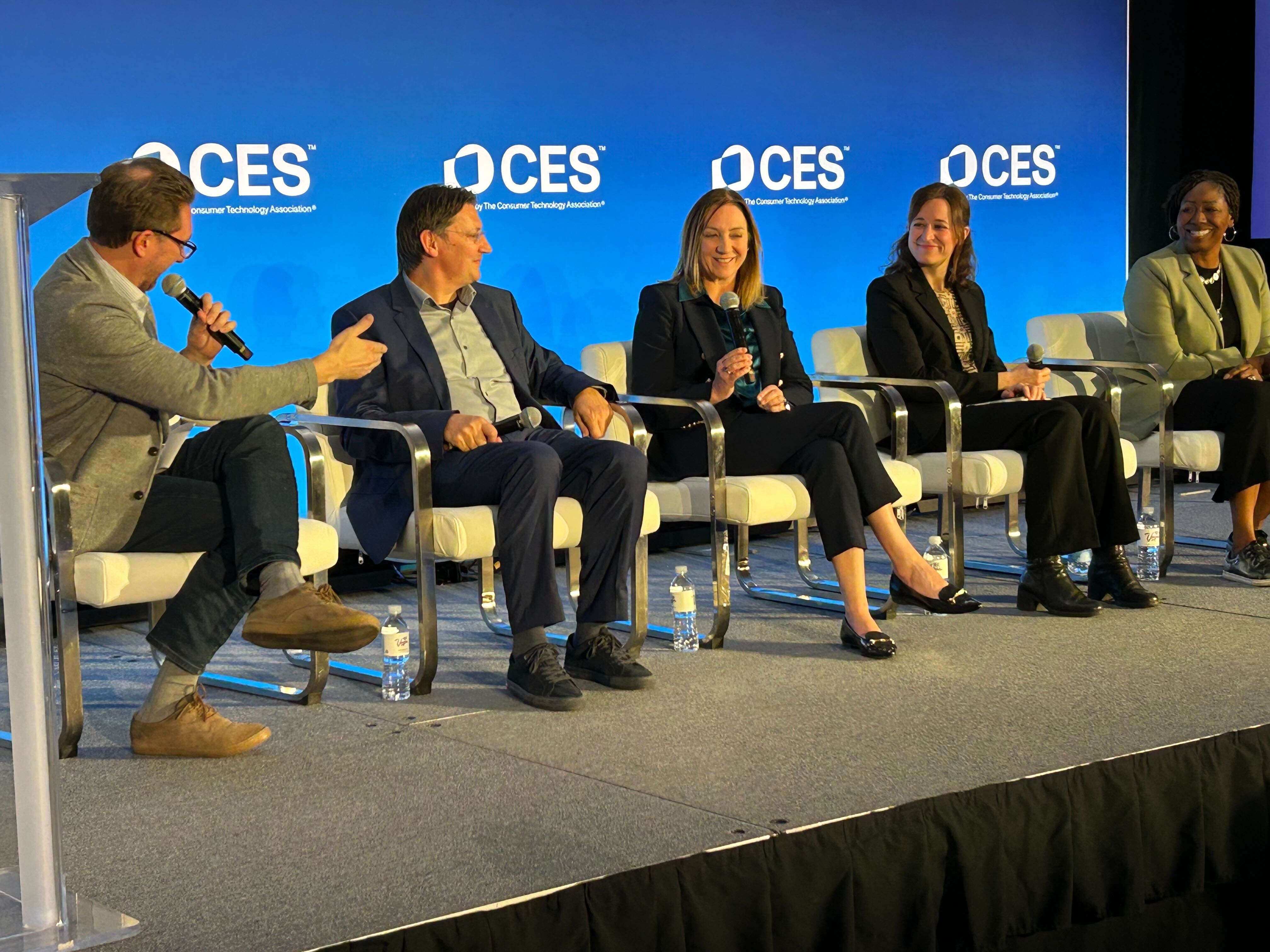 A panel of five seated people speaking on a stage.