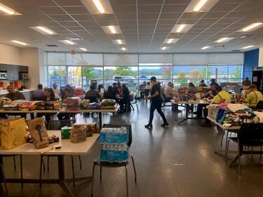 A room full of people gathered with chairs and boxes of supplies.