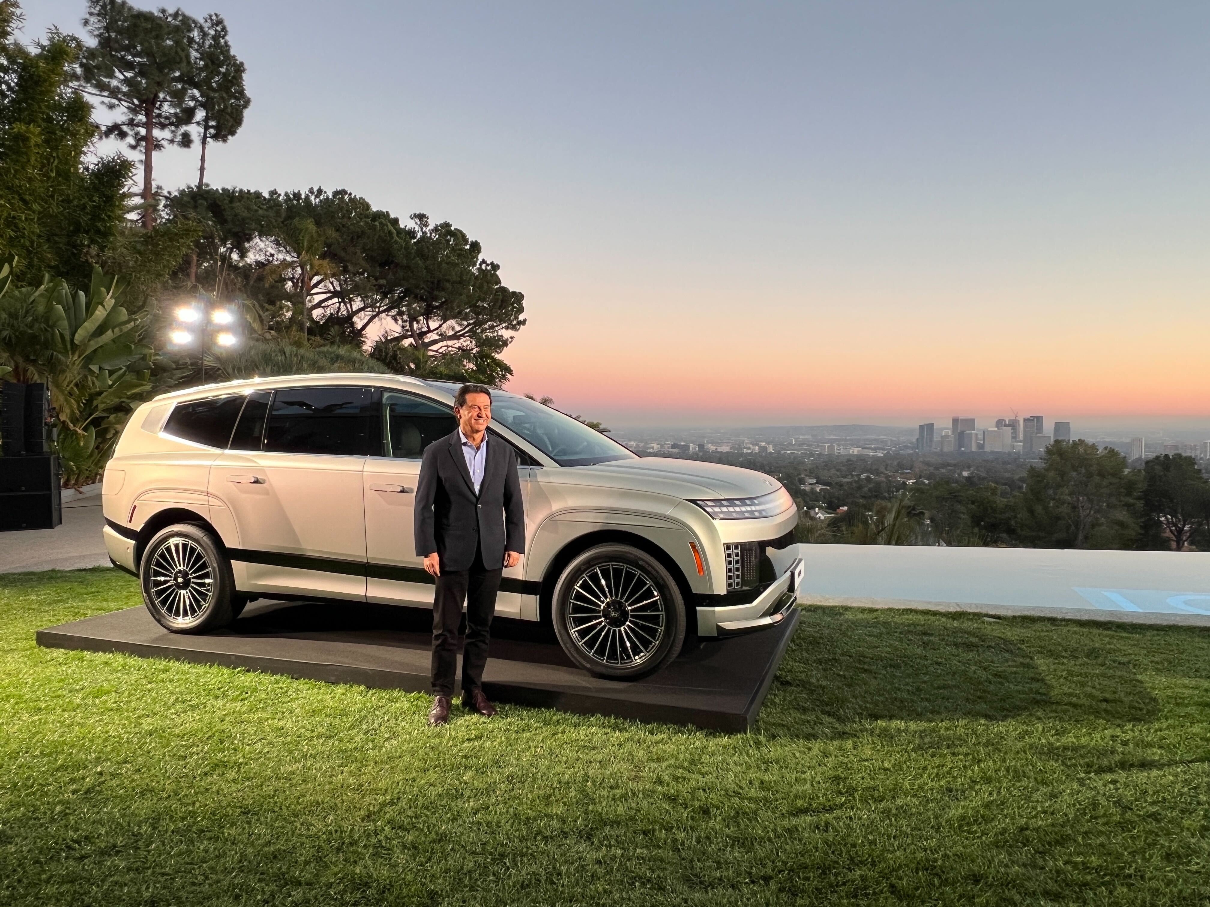 A white Hyundai Ioniq 9 electric three-row crossover with an executive standing near.