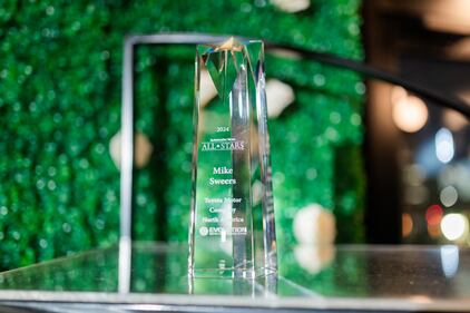 A crystal trophy on a stand at a gala event.