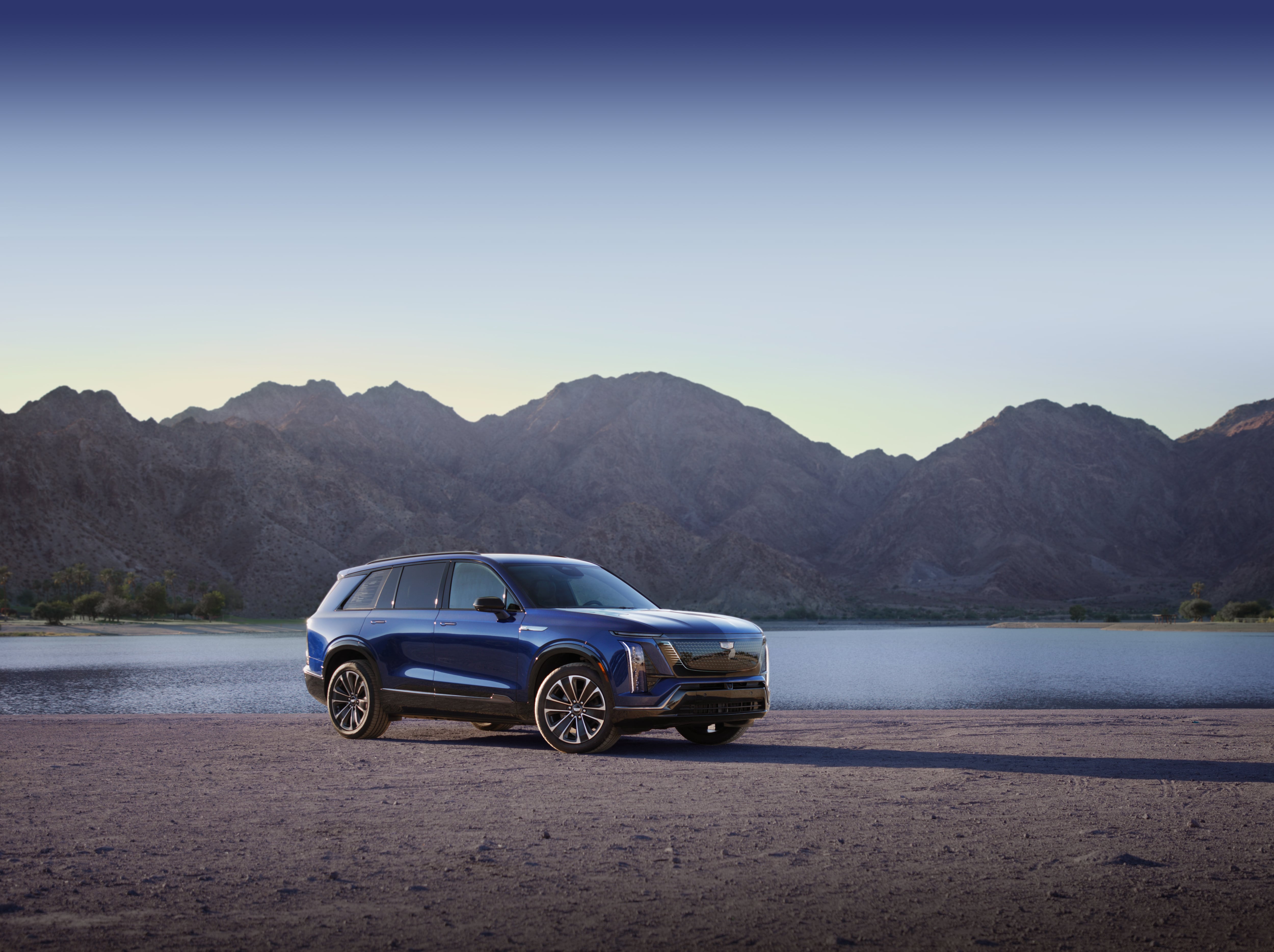 A side angle image of a blue vehicle, the 2026 Cadillac Vistiq, near water.