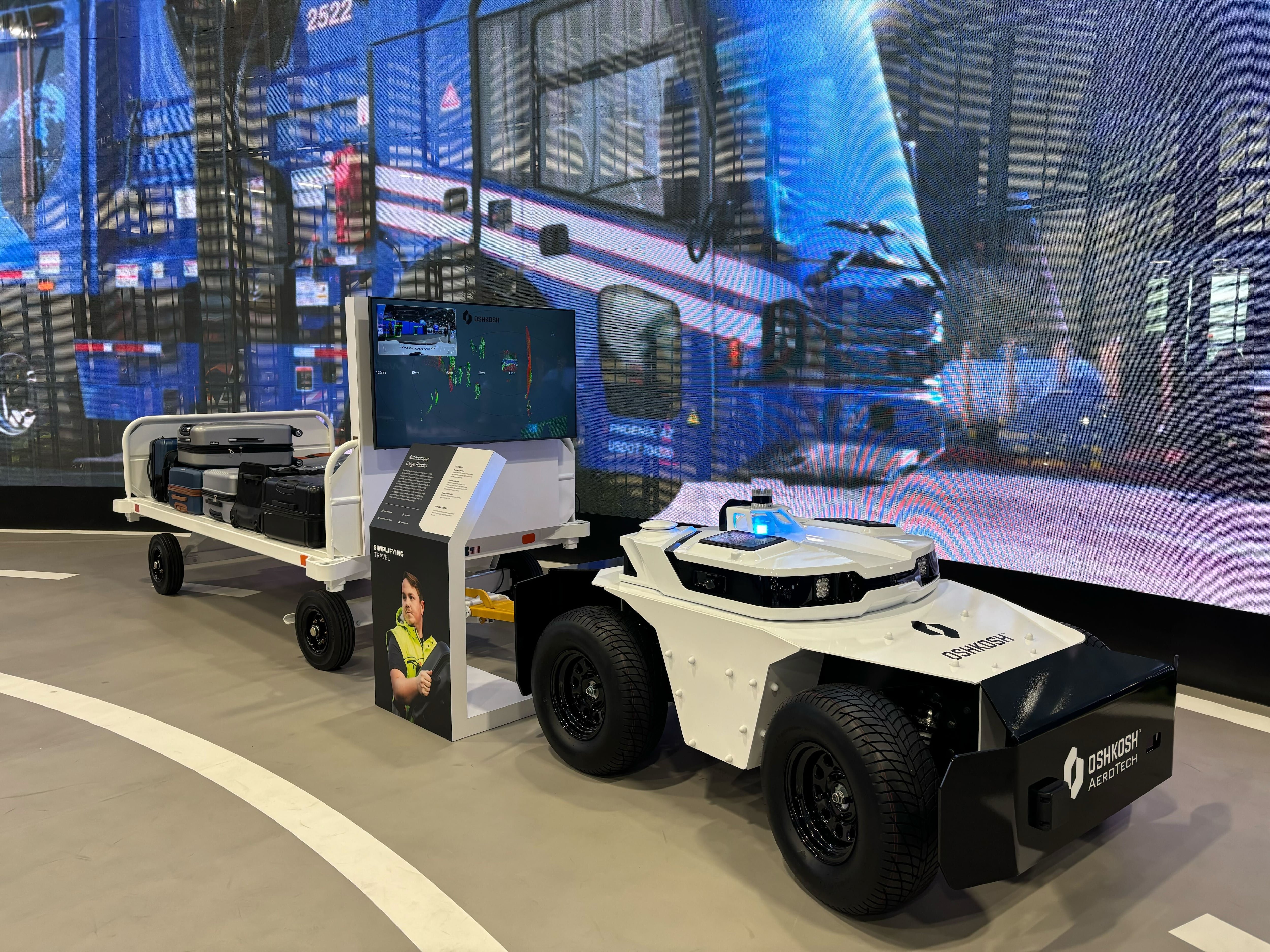 A robotic vehicle with wheels and a small trailer on display at a technology show.