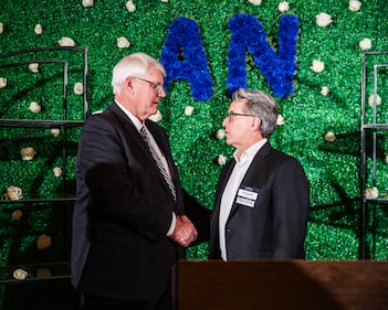 Two men shake hands at an awards event