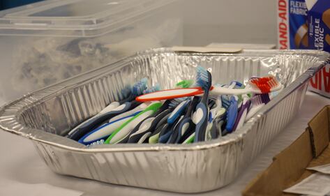 Toothbrushes piled high in a metal tray.