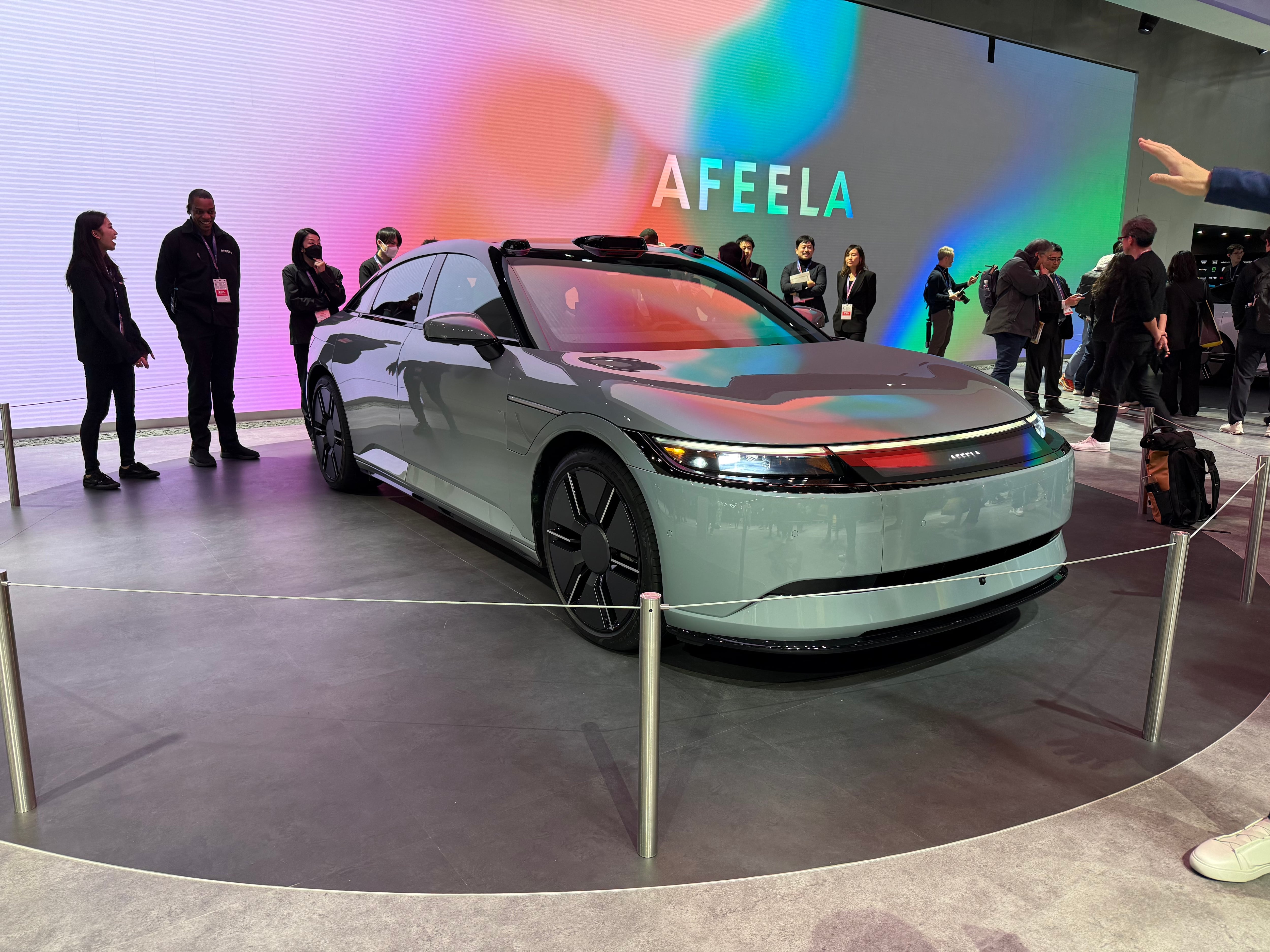 A white electric sedan on display at a technology show.