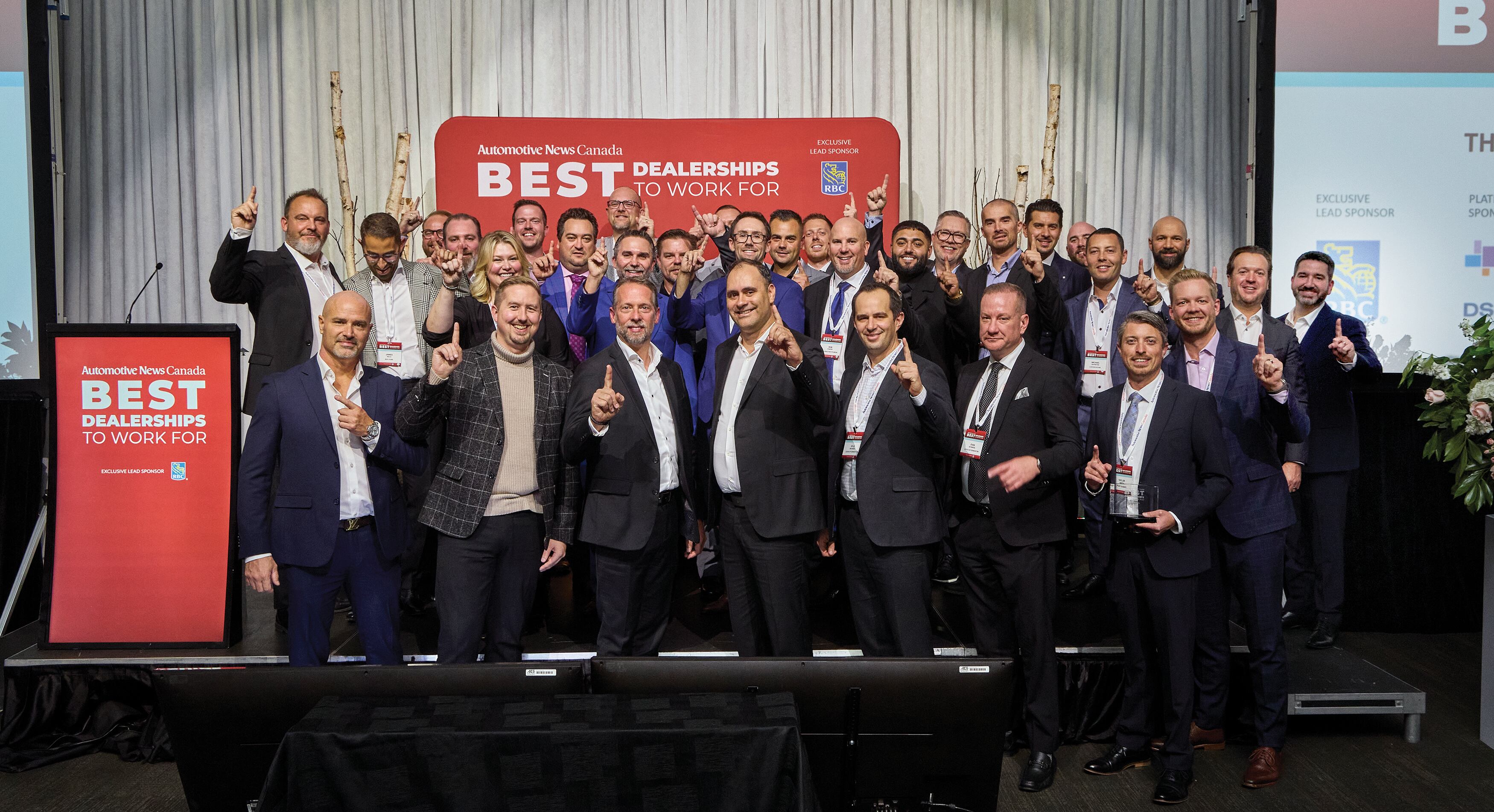 Automotive News Canada Best Dealerships winners cheer in a group photo on stage in Toronto